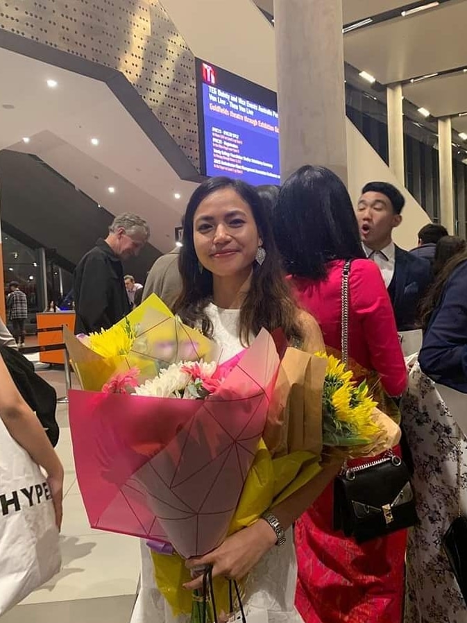 A young Cambodian woman smiles while holding a bunch of flowers