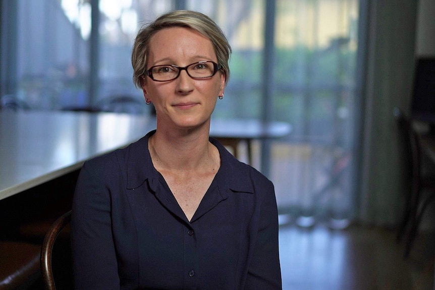 A woman wearing glasses and a blue collared shirt.