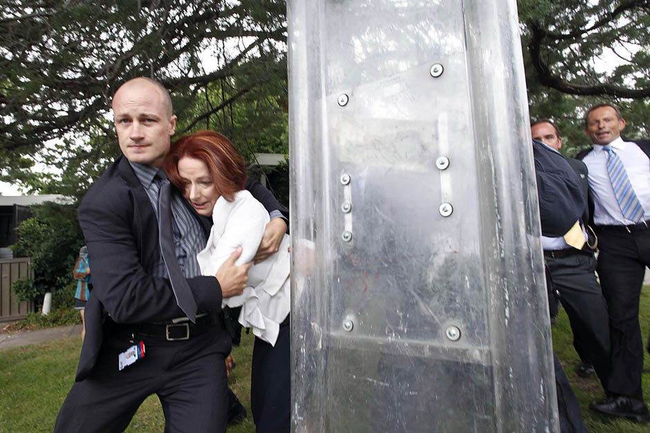 Prime Minister Julia Gillard is escorted by police and bodyguards.