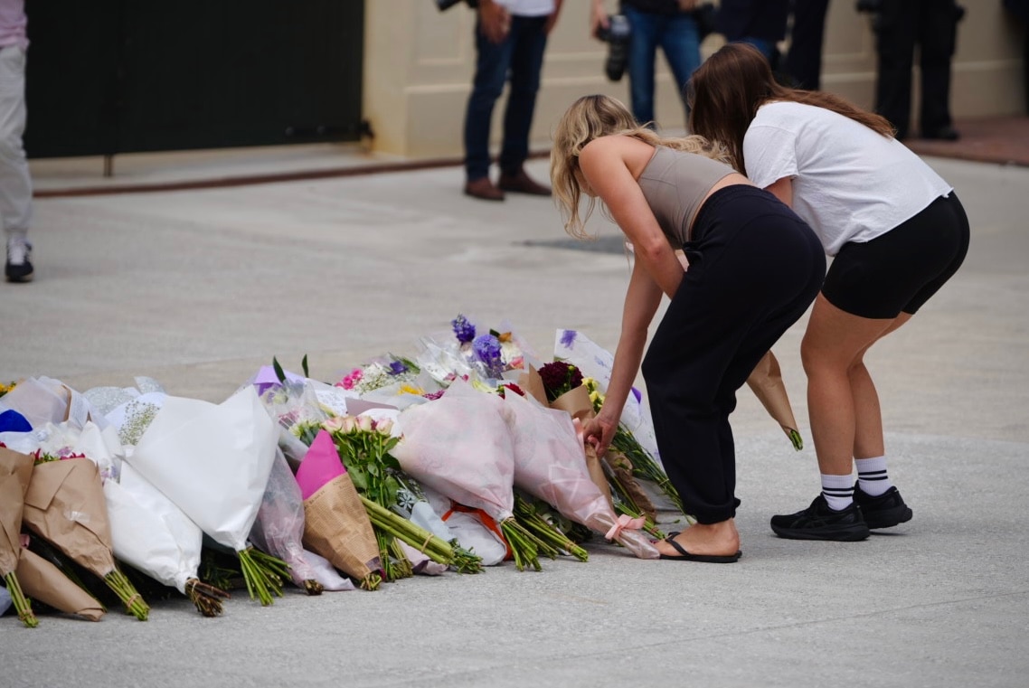 Duas pessoas colocando flores no chão.
