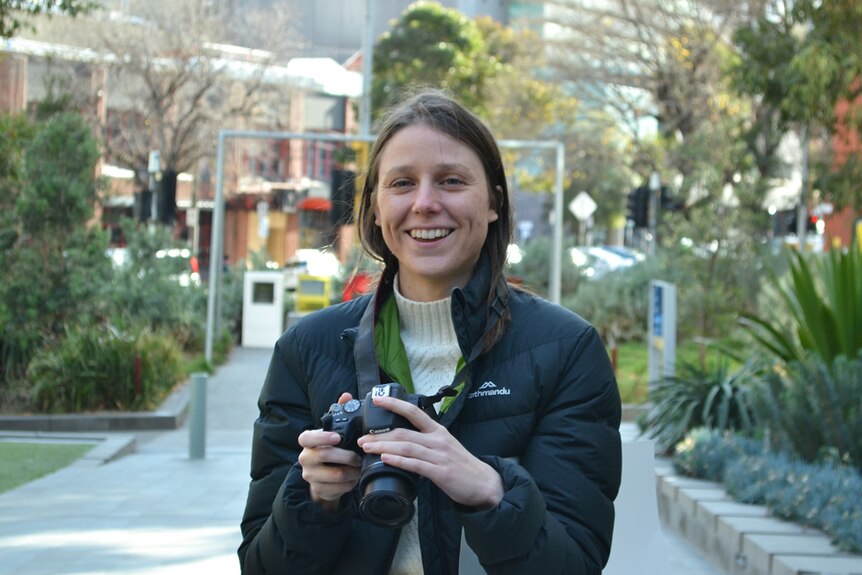 Jessica Leanne holds her camera in a courtyard