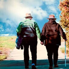 Older couple walking along a road hand-in-hand