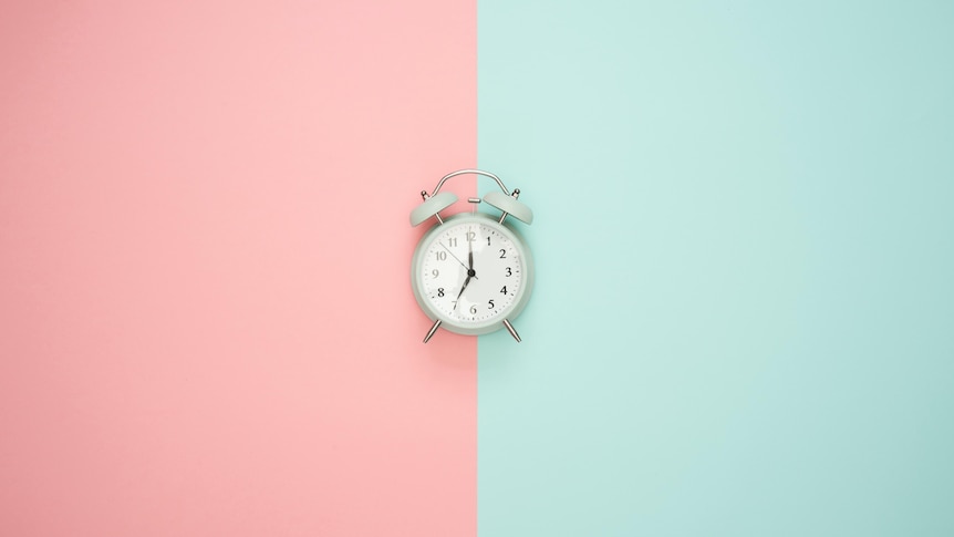A small clock with a pink and green background.