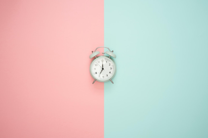 A small clock with a pink and green background.