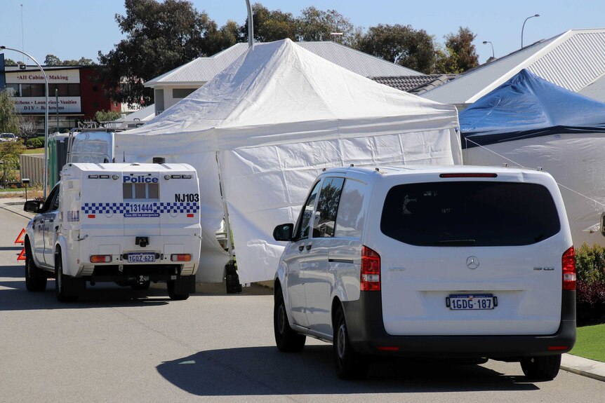A police car and white can outside a suburban house obscured by two large tents.