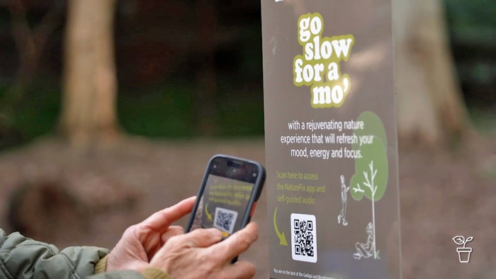 Person scanning a QR Code on a sign in the bush.