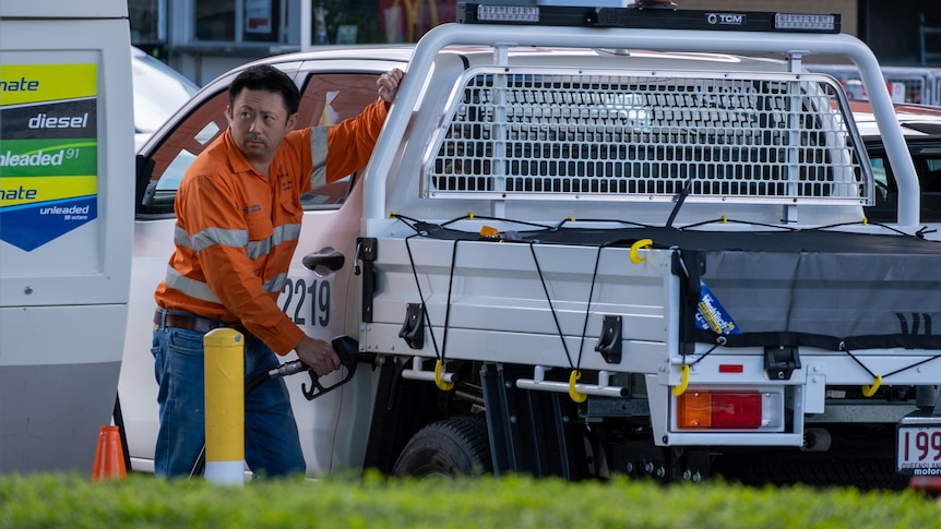 A man fills his ute with petrol. 