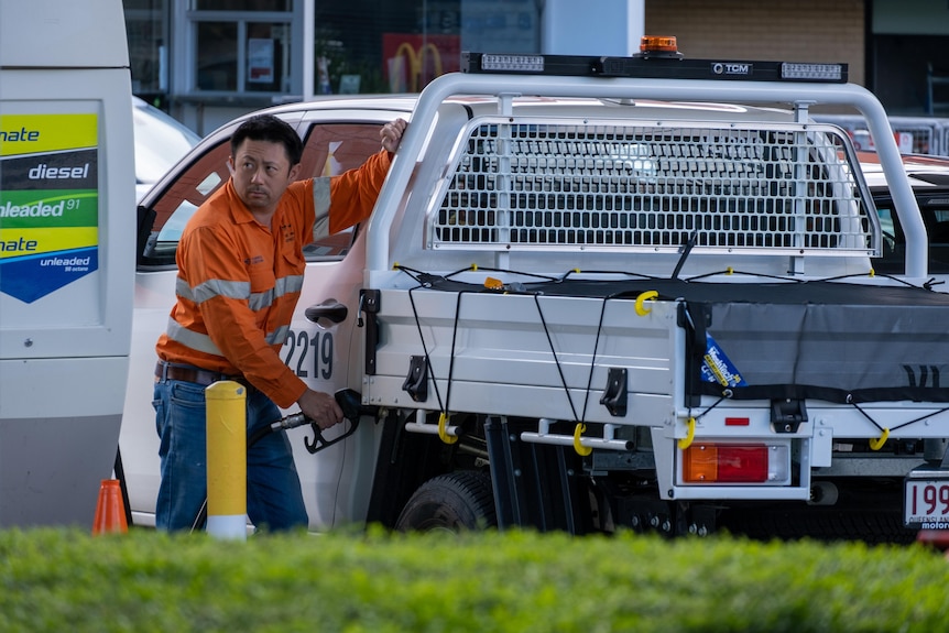 A man fills his ute with petrol. 