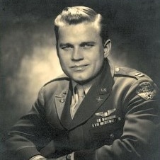 A man dressed in an Air Force uniform smiles at the camera in a black and white photo.