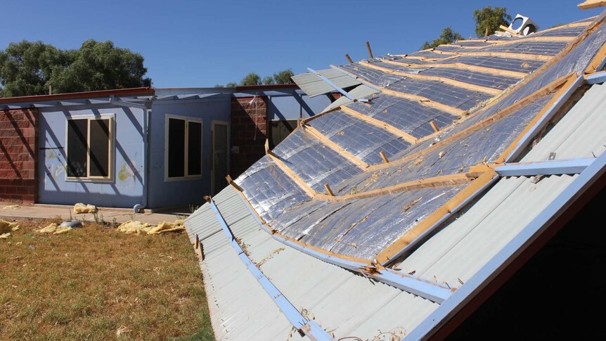 The roof of a single storey house half blown off