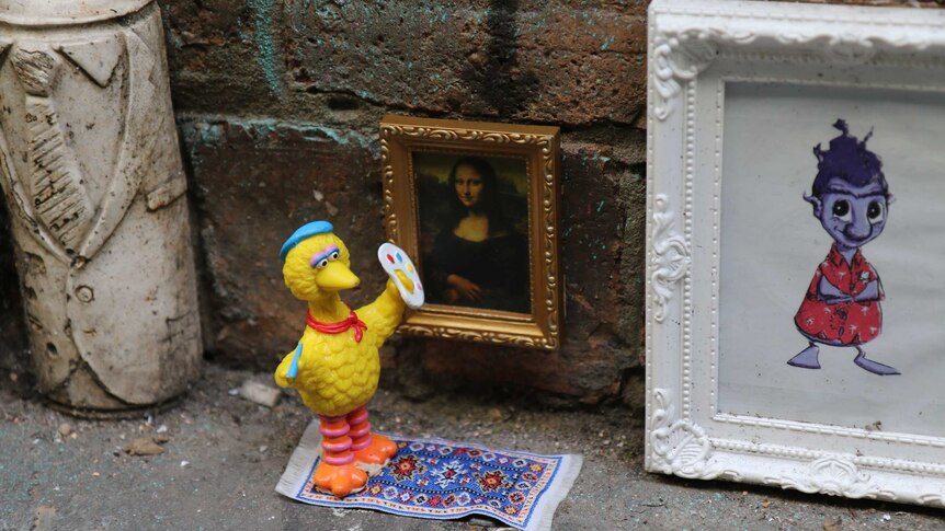 A miniature diorama featuring big bird painting the Mona Lisa