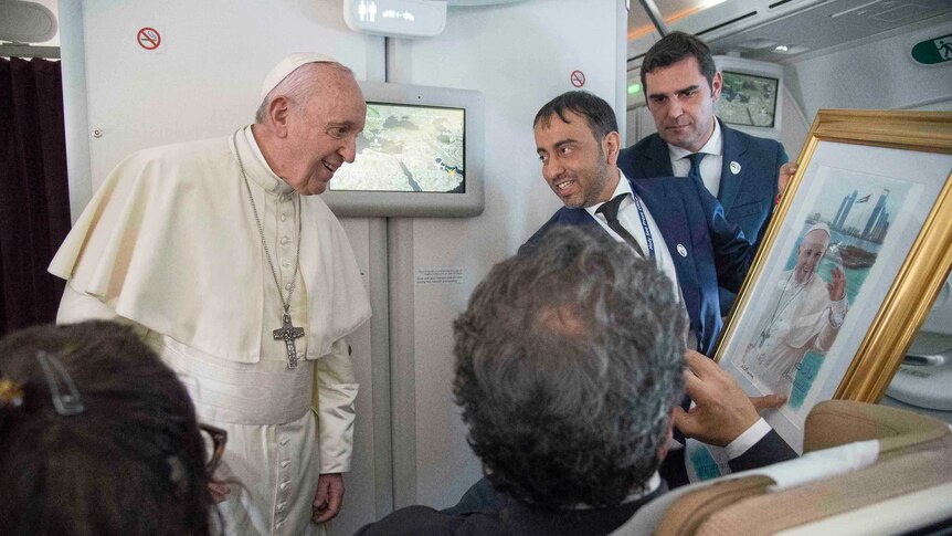 Pope Francis receives a gift, a gold framed photograph of himself, aboard the papal plane.