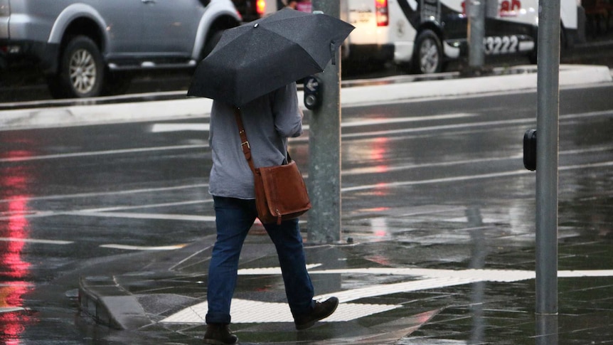 A man walks along a South Brisbane street in the rain.
