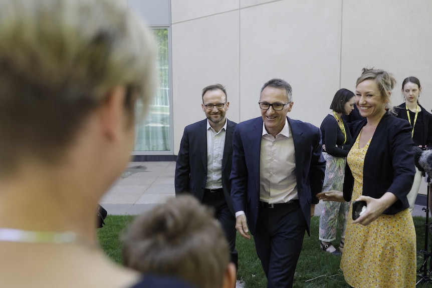 Lucy Quarterman puts her hands on her sons' backs as they watch Richard Di Natale address the media