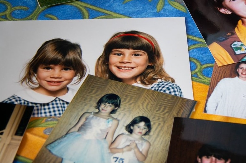 Photographs laid out on a table of two young girls in school uniforms, and in dancing costumes.