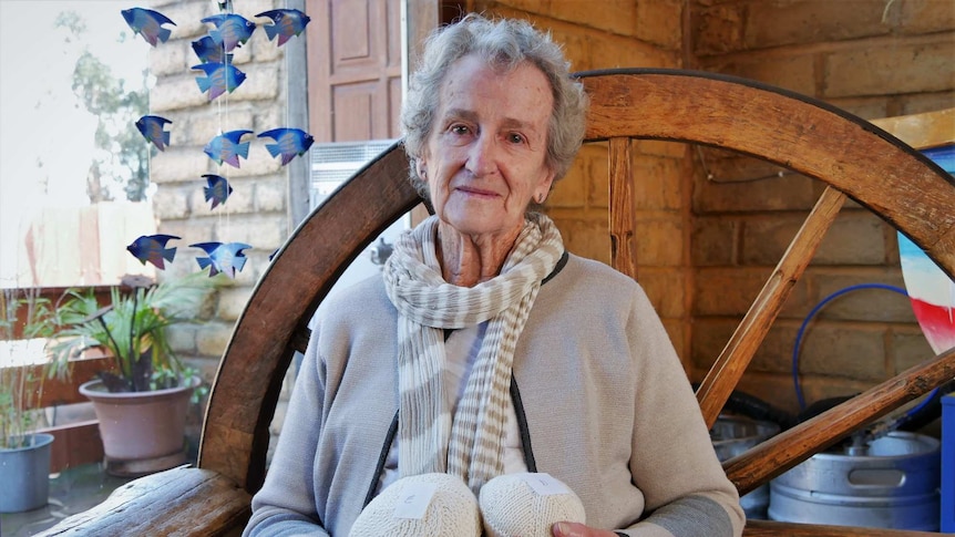 Illma Read sitting on a bench and holding a pair of knitted knockers.