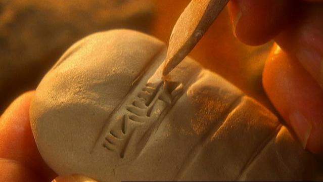 A hand holds a stone with cuneiform carved into it