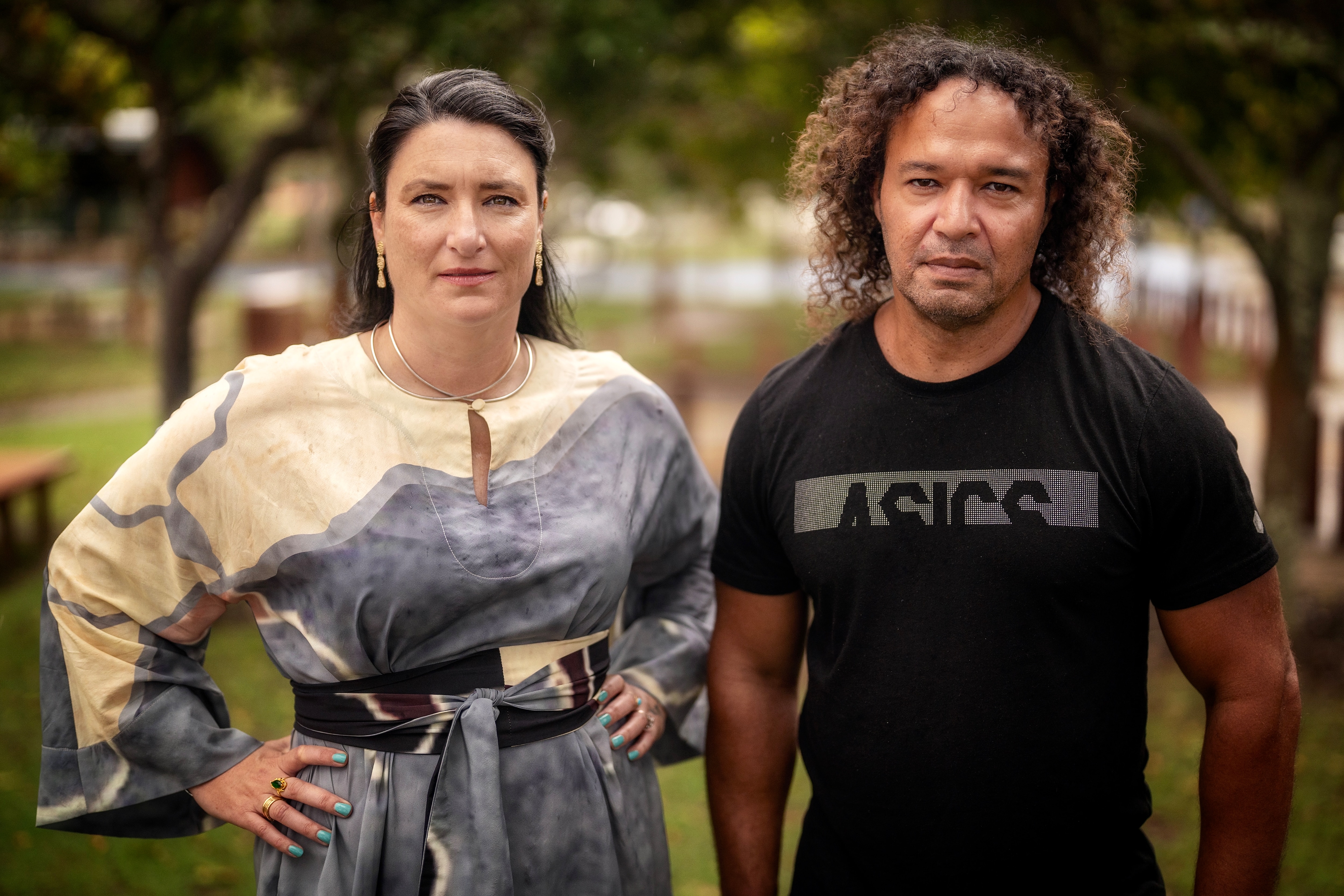 Woman in a white and blue dress with her hands on her hips standing next to a man in a black t-shirt.