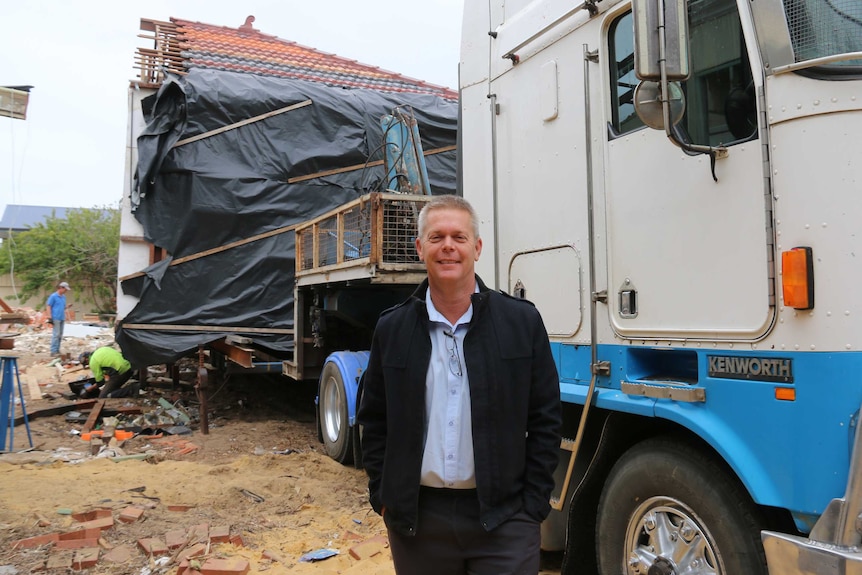 Phil Jenner stands in front of a house on a semi-trailer.