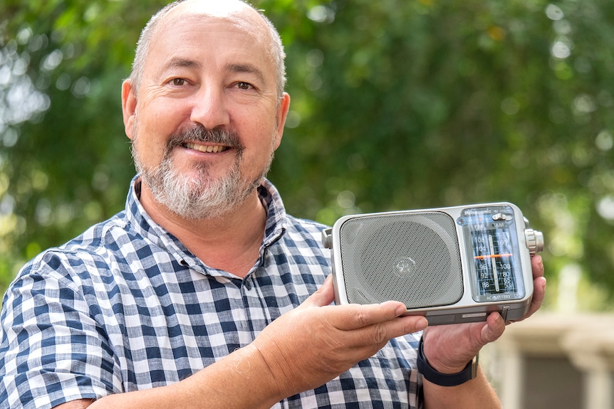 A man smiles holding a radio.