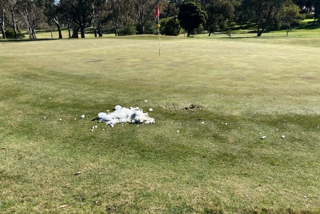Ice on a golf green near a hole, marked with a flag