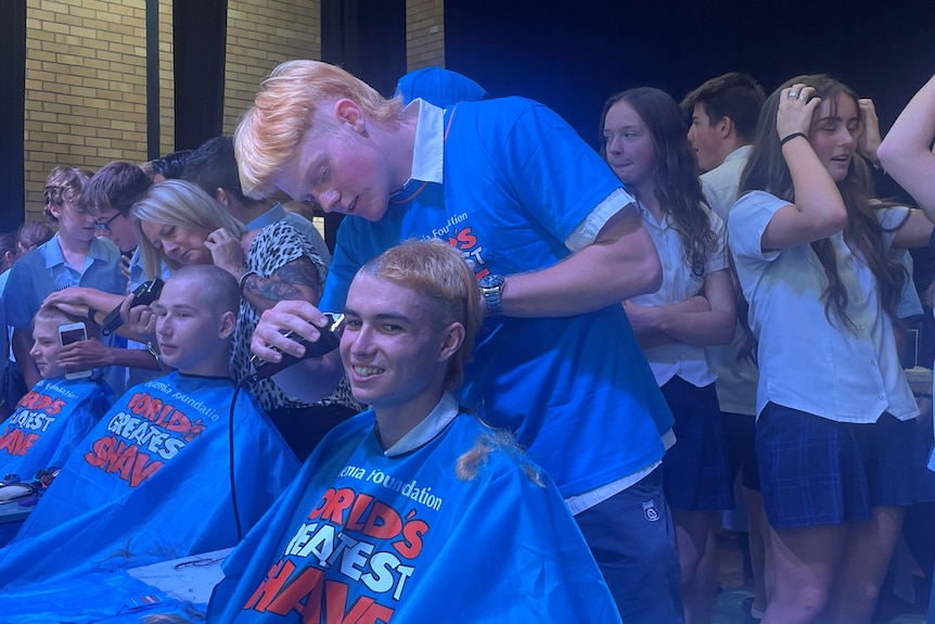 A student shaves another student's hair at a world's greatest shave fundraiser.