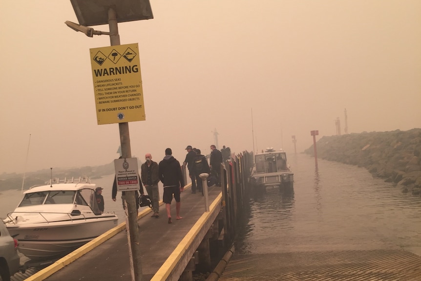 Brown-grey smoke covers a pier, jutting out into the water.