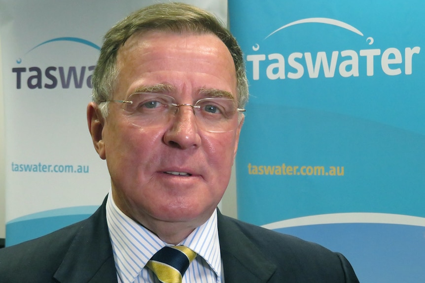 Miles Hampton seated in front of TasWater signage.
