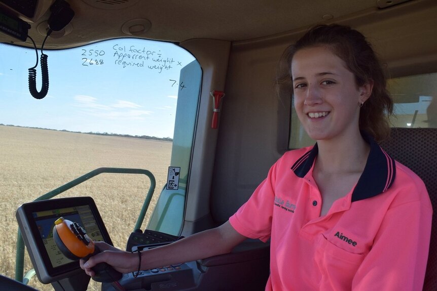 A woman wearing a pink hi vis shirt sitting in a tractor
