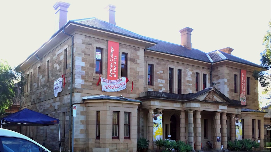 A sandstone building with banners hanging from the upstairs windows.