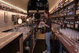 A woman drying a glass at a bar