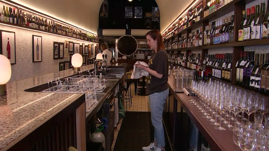 A woman drying a glass at a bar