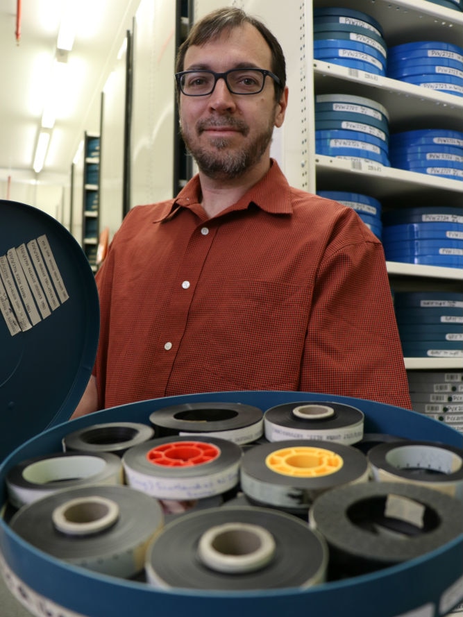Jon Steiner holding an open can with several rolls of film inside.
