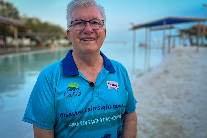 A man with a blue polo stands on the esplanade in Cairns.