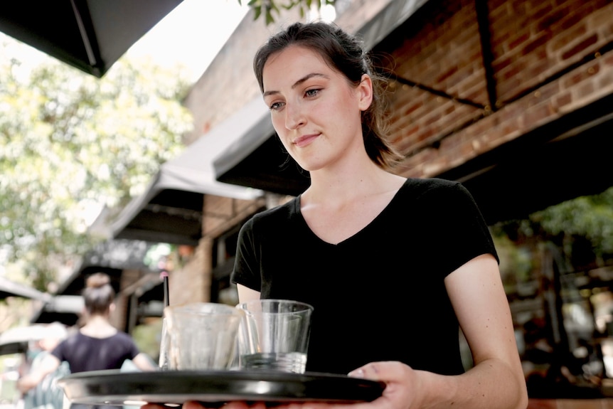 A woman is waiting a table.