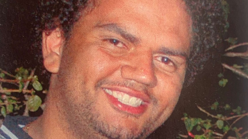 A photo of a smiling Raymond Noel Thomas wearing a silver top outside at night time.