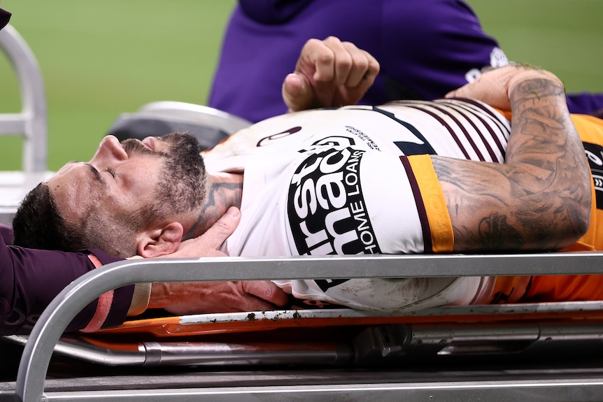 A Brisbane Broncos NRL player is taken from the field on a medicab.