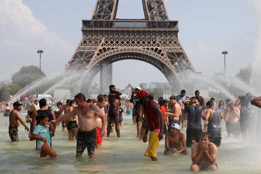 You look at the base of the Eiffel Tower in Paris from within nearby fountains within people in them on a clear day.