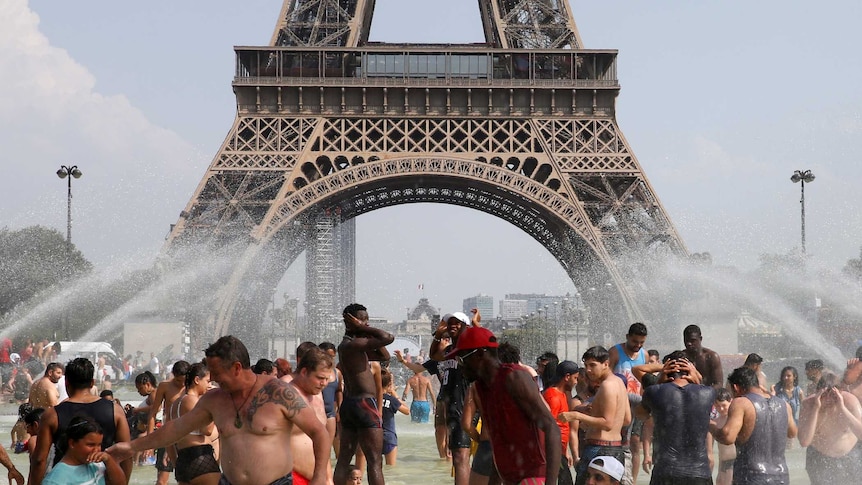 You look at the base of the Eiffel Tower in Paris from within nearby fountains within people in them on a clear day.