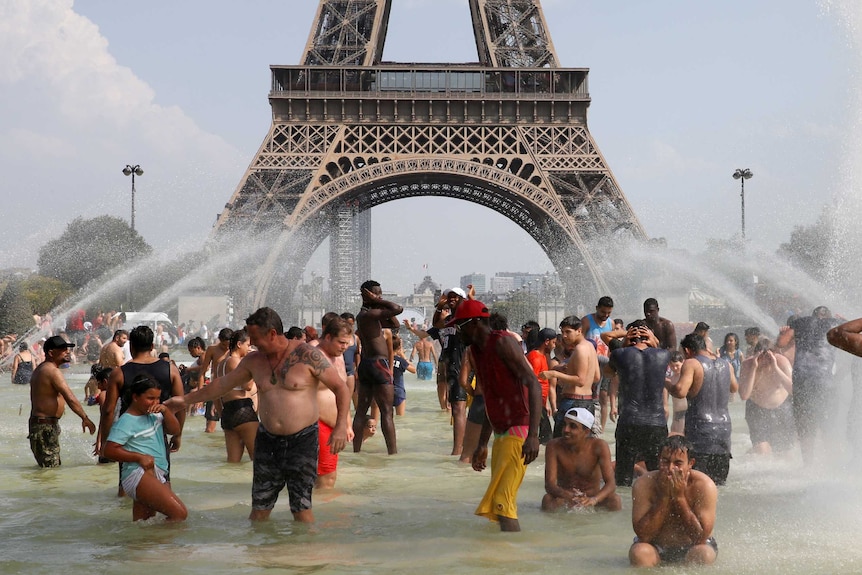 You look at the base of the Eiffel Tower in Paris from within nearby fountains within people in them on a clear day.