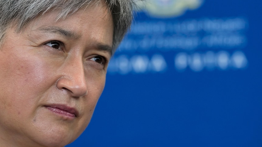 A close up of Penny Wong with scrutinising eyes against a blue background.