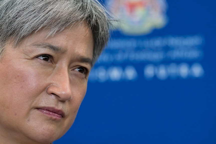 A close up of Penny Wong with scrutinising eyes against a blue background.