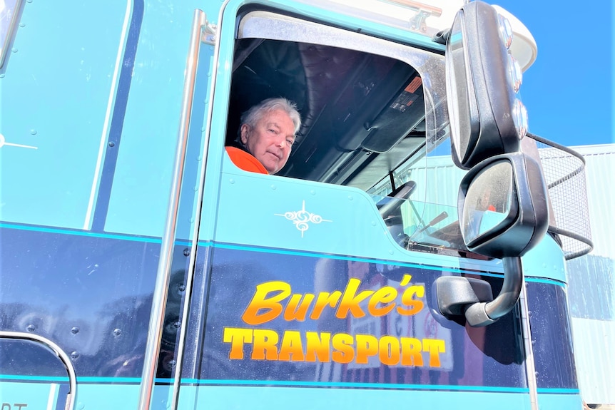 A man sitting in the cab of a truck looking at the camera.