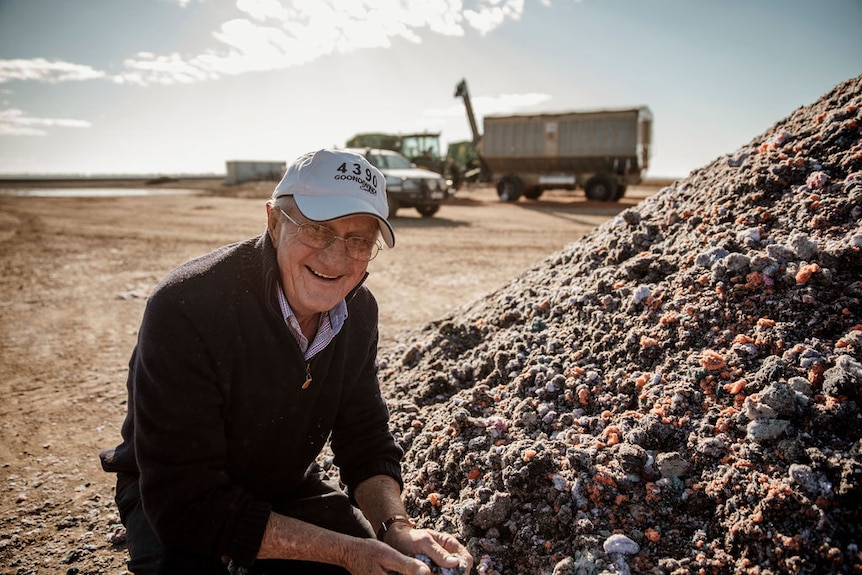 Man in paddock holds textile waste.