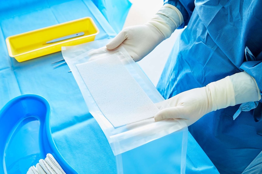Biodegradable plastic medical scaffold NovoSorb BTM being removed from packaging by a medical professional.