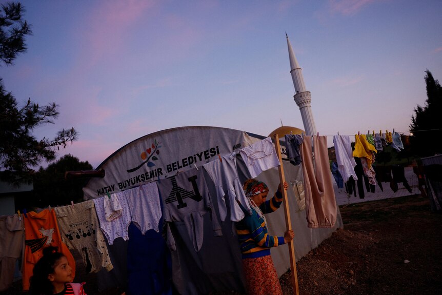 A woman next to a washing line with clothes hanging on it. 