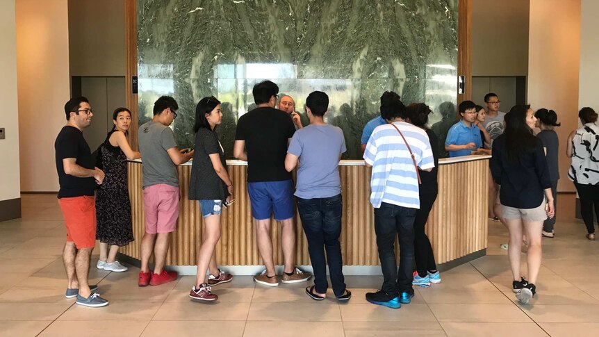 people at a reception with worker behind desk holding phone