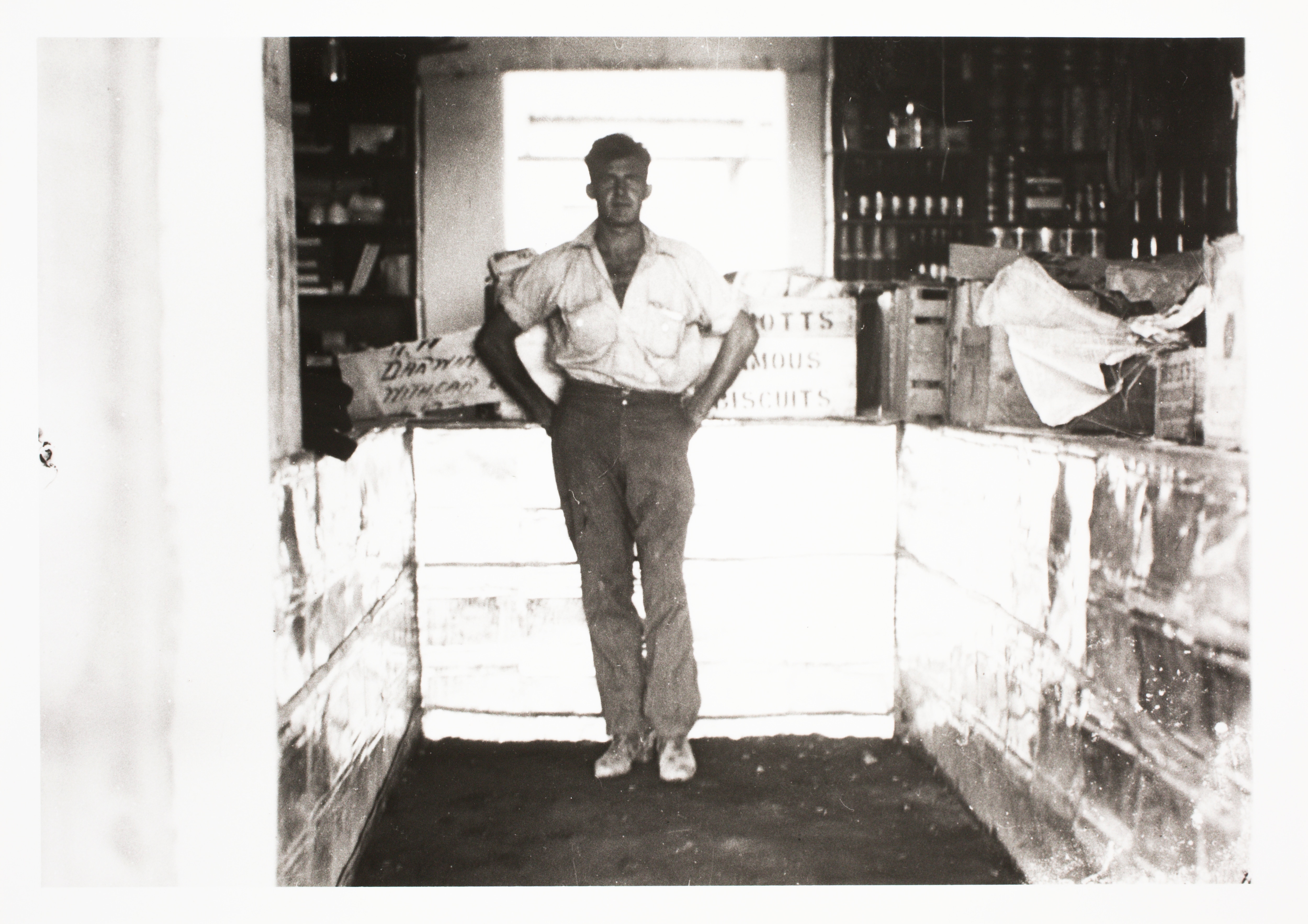 A black and white photo of a man in a shop.
