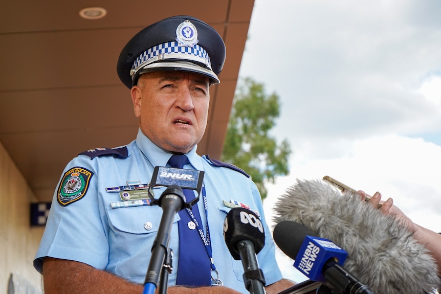 A middle-aged, uniformed policeman speaks to the media.