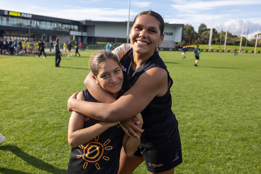 A female footy player hugs another player on field